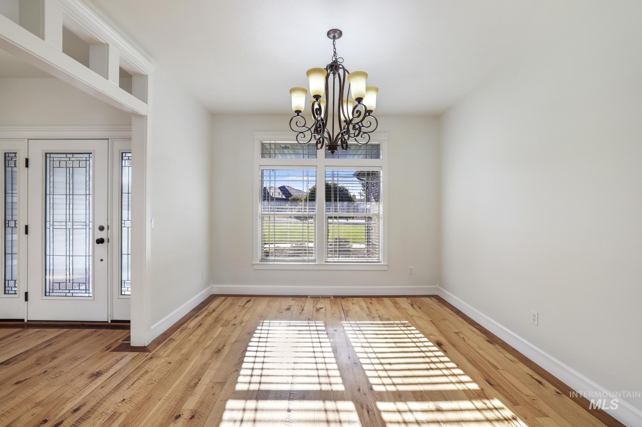 Unfurnished dining area with a chandelier and light wood-style floors