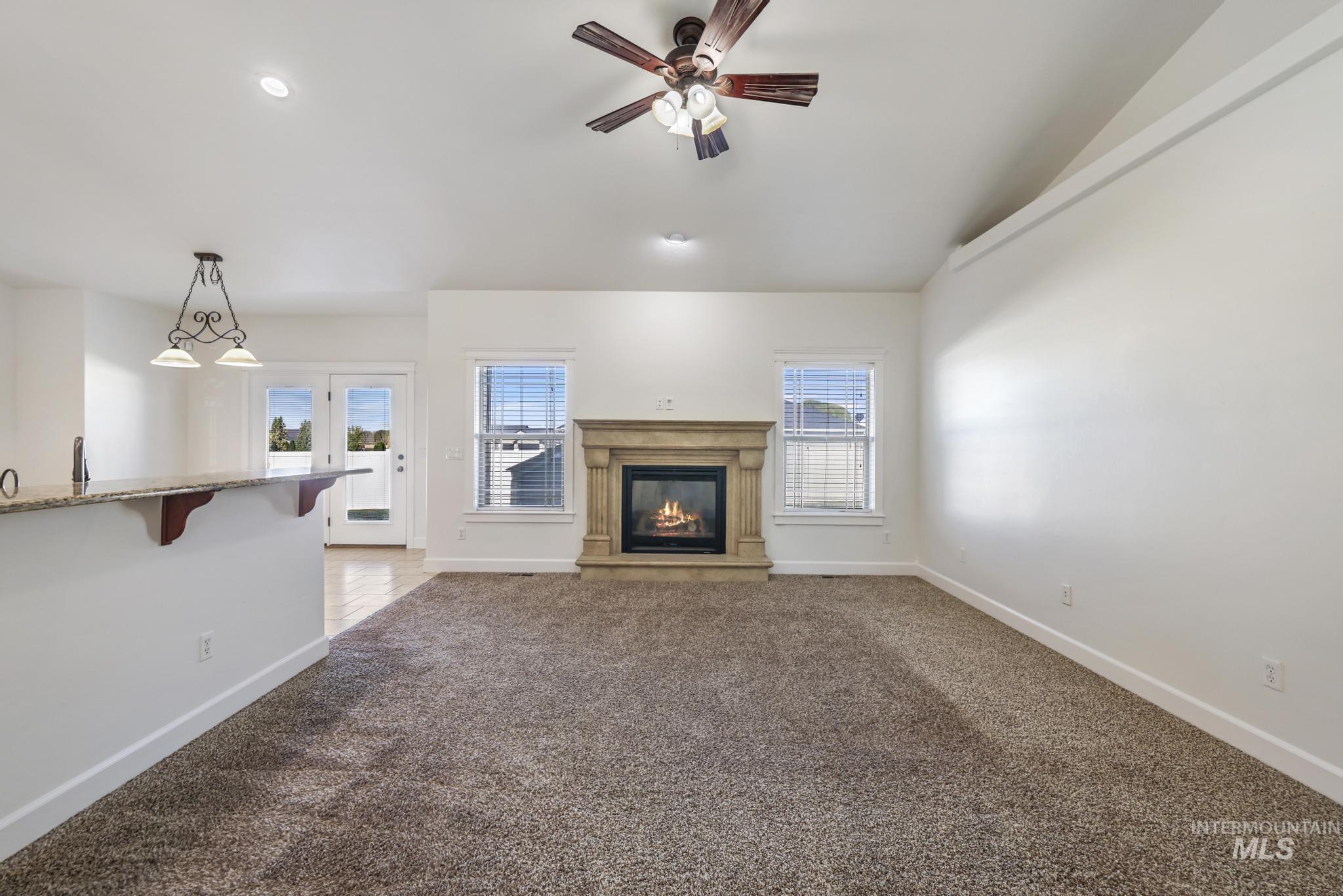 Unfurnished living room with dark carpet, ceiling fan, a fireplace, recessed lighting, and vaulted ceiling