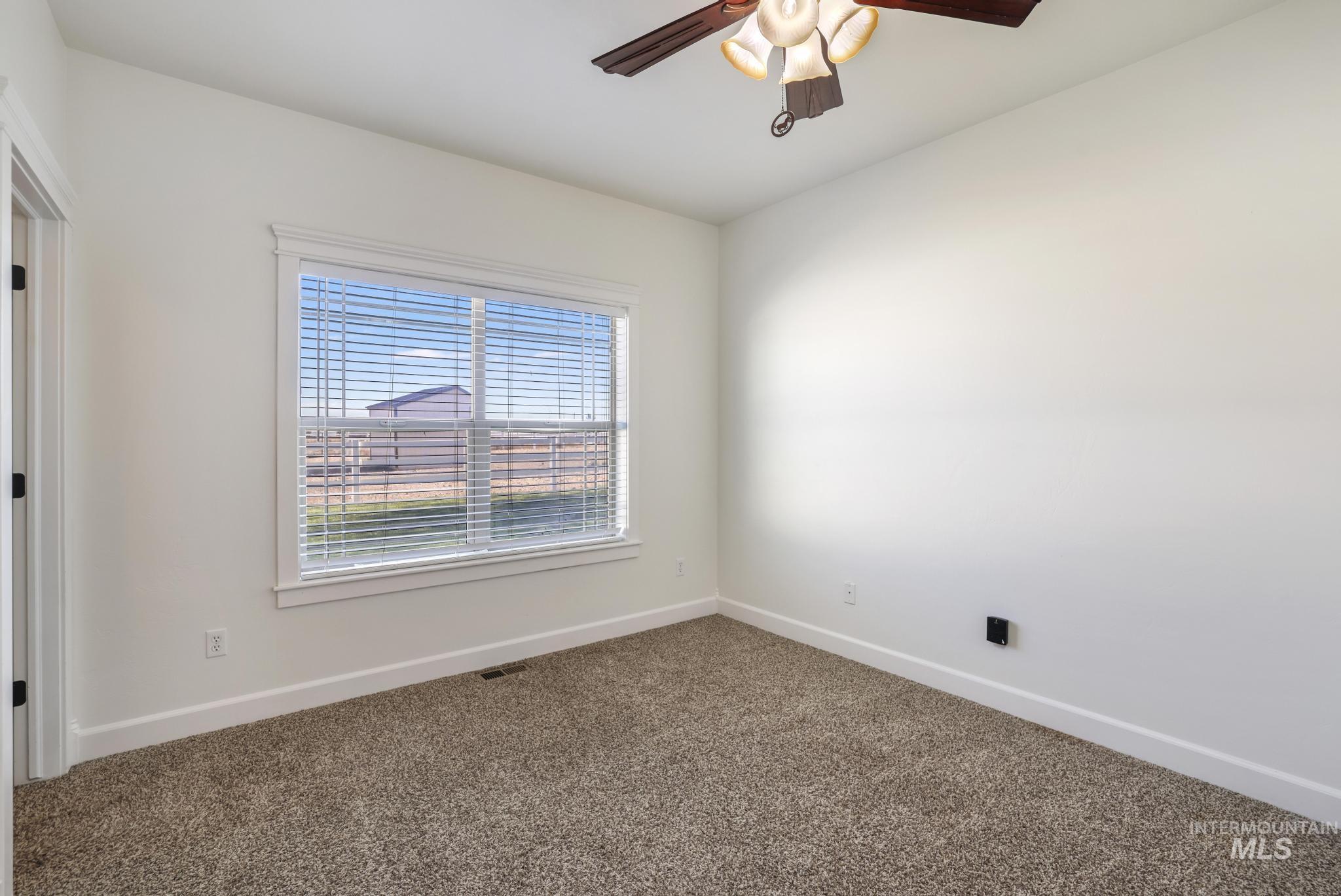 Spare room with carpet and a ceiling fan