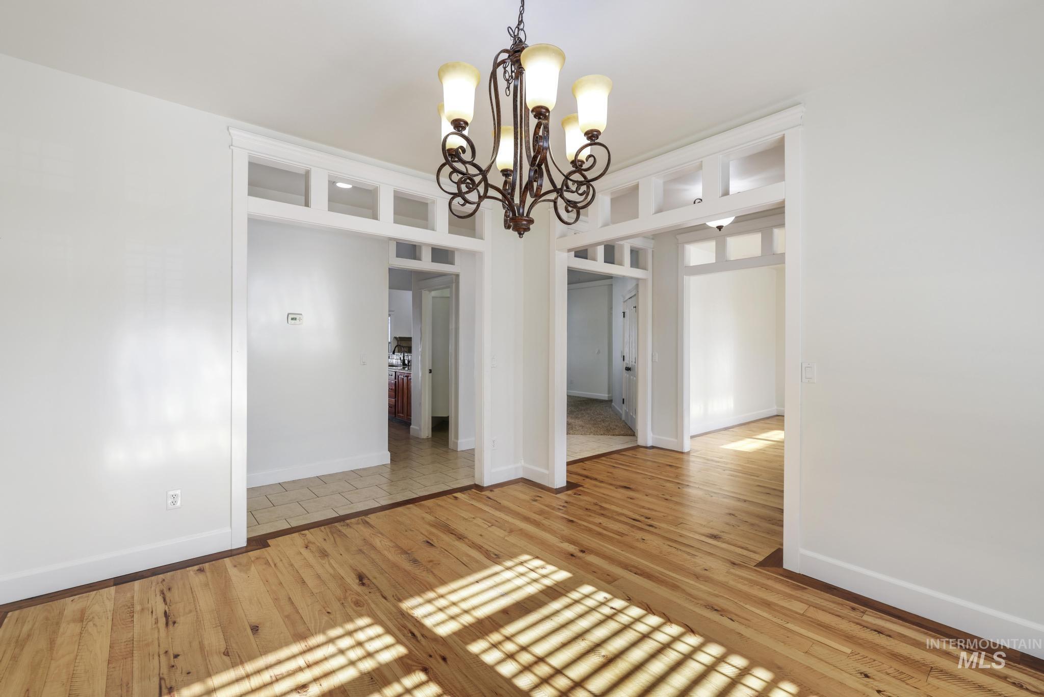 Empty room featuring light wood-style flooring and a chandelier
