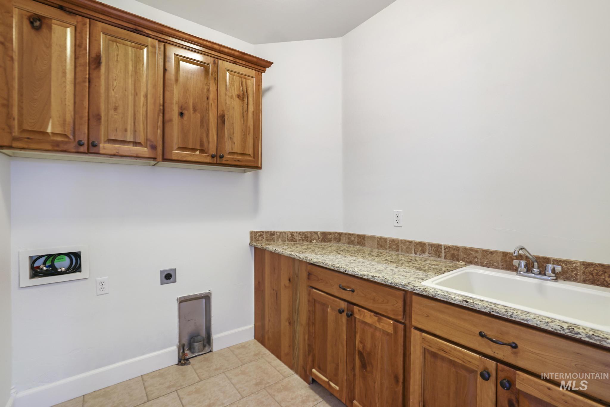 Laundry room with light tile patterned floors, cabinet space, electric dryer hookup, and washer hookup