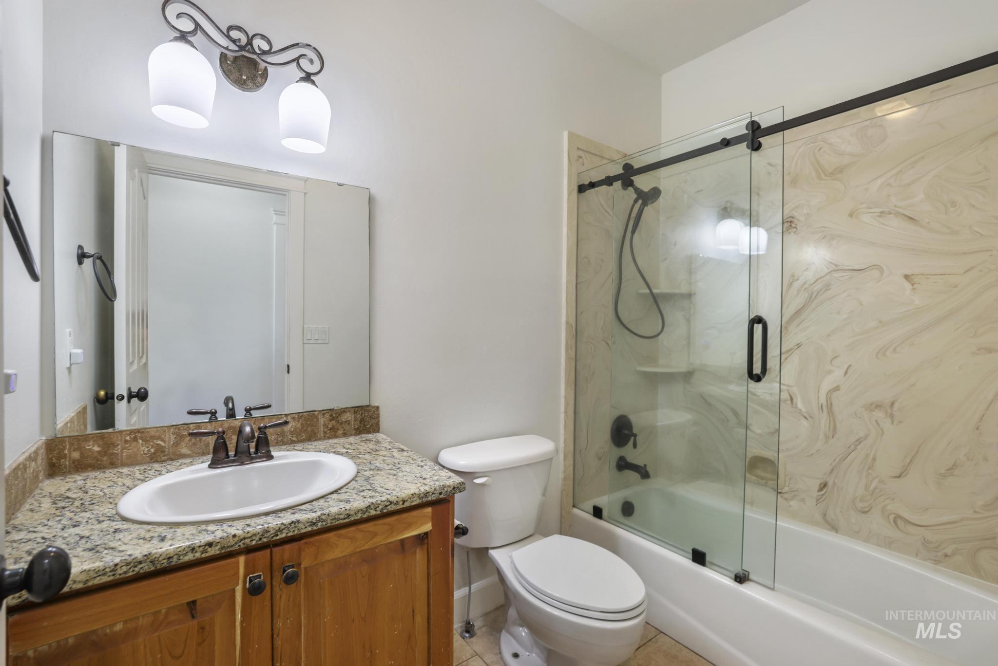 Bathroom with shower / bath combination with glass door, vanity, and light tile patterned floors