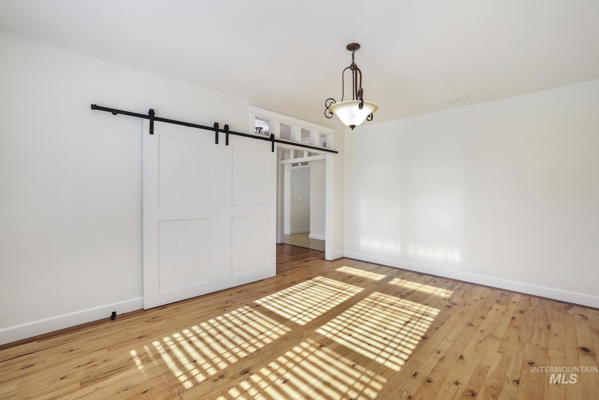 Unfurnished bedroom featuring a barn door and light wood-style floors