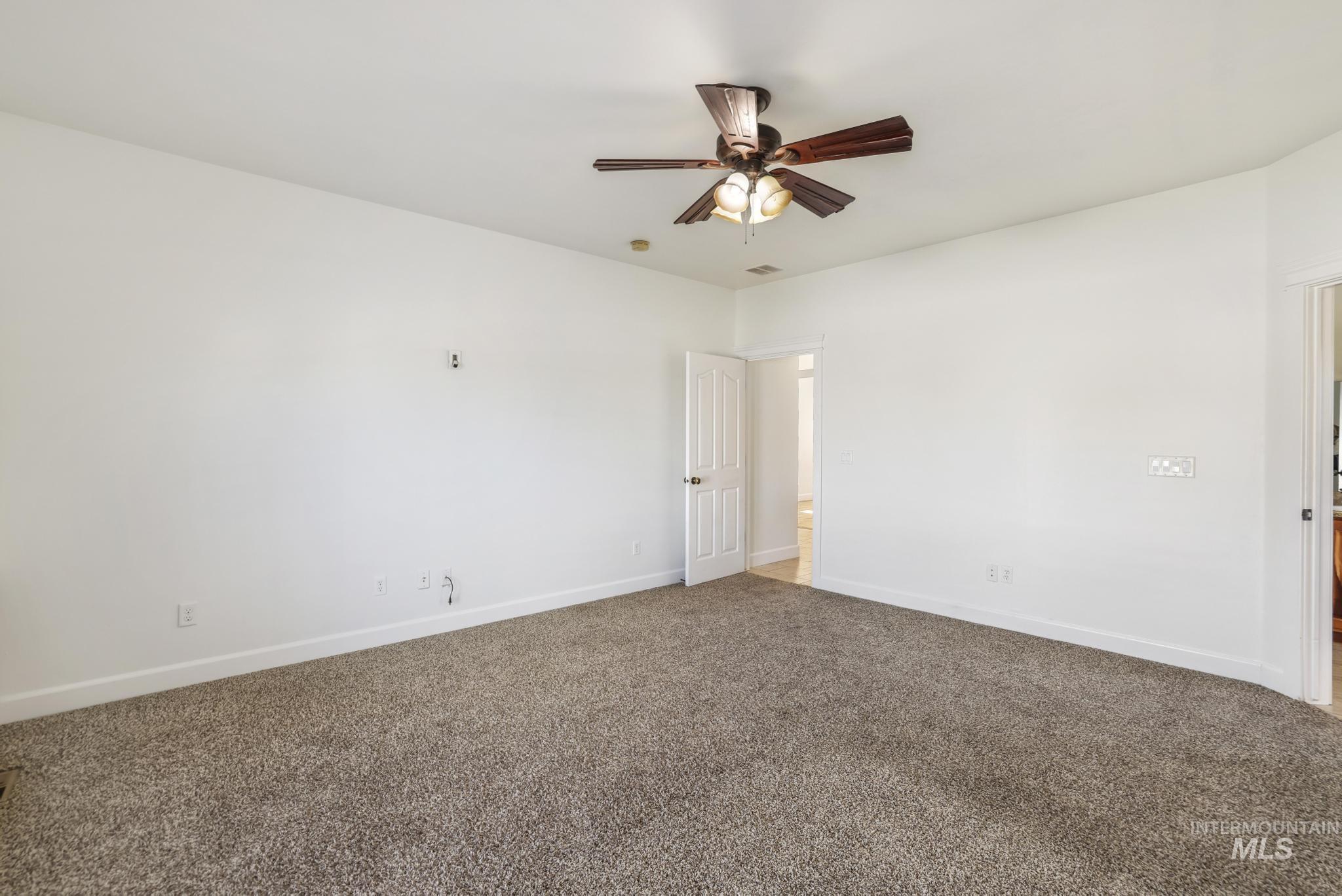 Carpeted spare room featuring baseboards and a ceiling fan