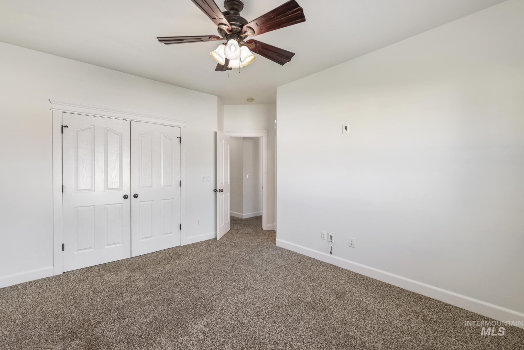 Unfurnished bedroom with carpet, a closet, and a ceiling fan