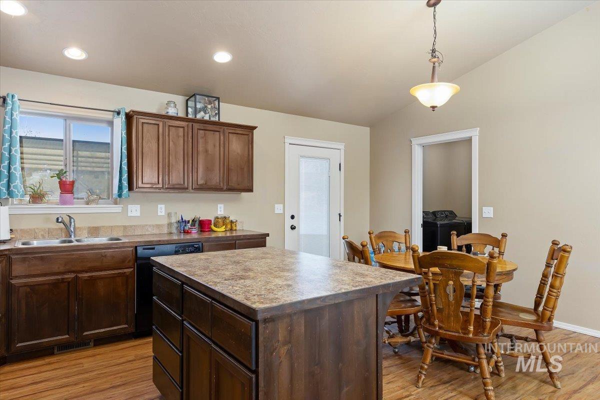 Kitchen with a kitchen island, light wood-style floors, hanging light fixtures, black dishwasher, and recessed lighting