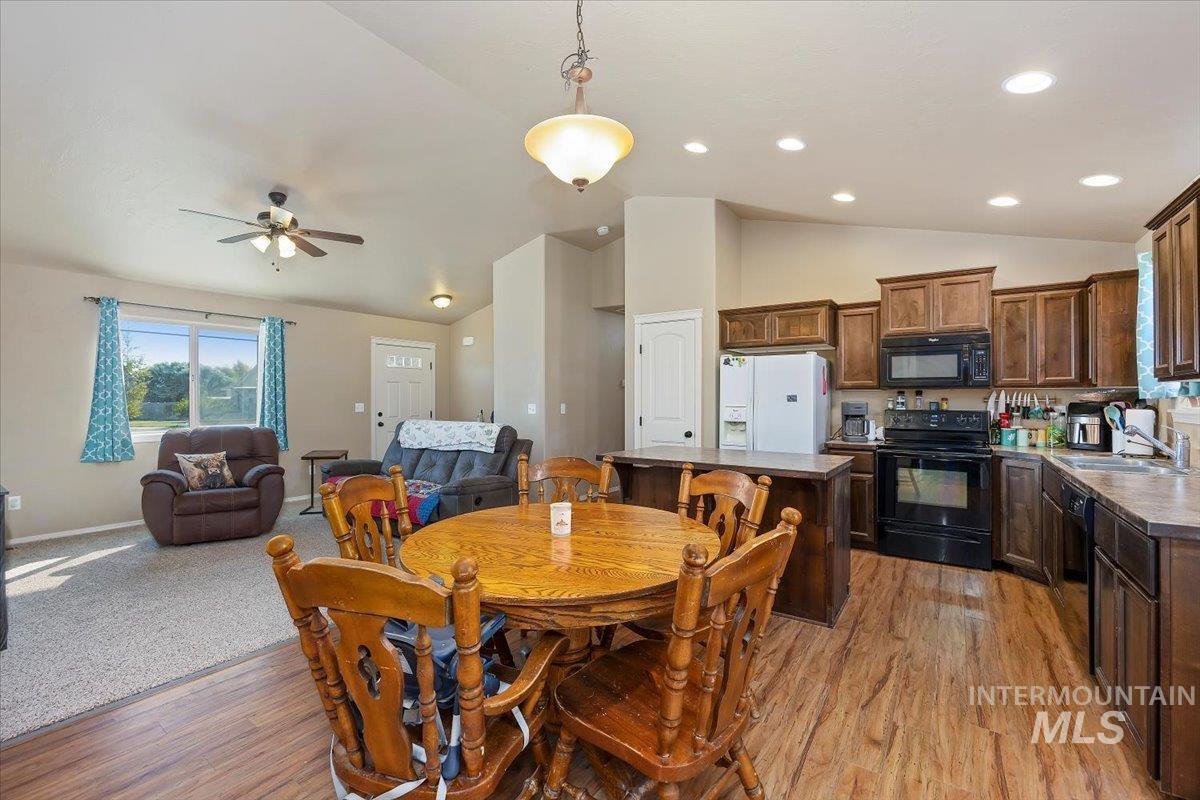 Dining room featuring light wood-style floors, ceiling fan, and high vaulted ceiling