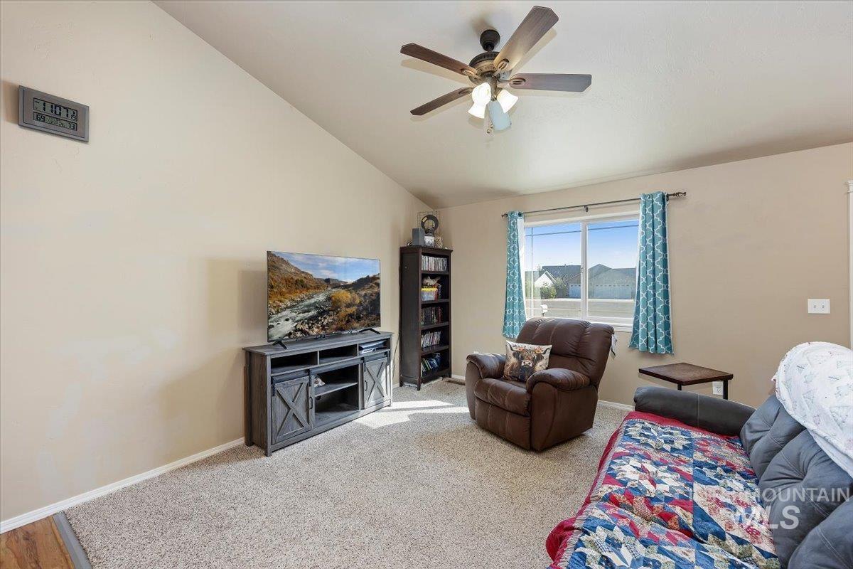 Carpeted living room featuring vaulted ceiling and ceiling fan