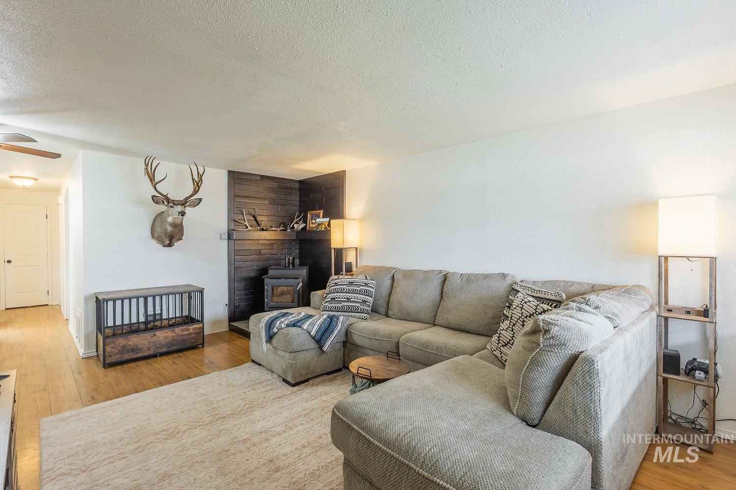 Living room with light wood-style flooring, a textured ceiling, and a wood stove