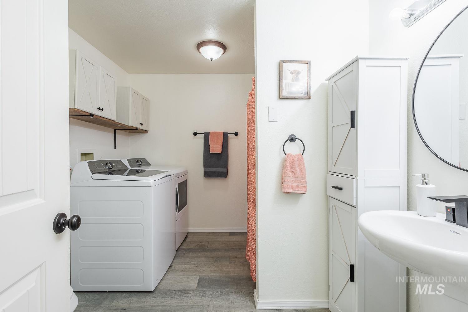 Laundry room with separate washer and dryer and light wood-style flooring