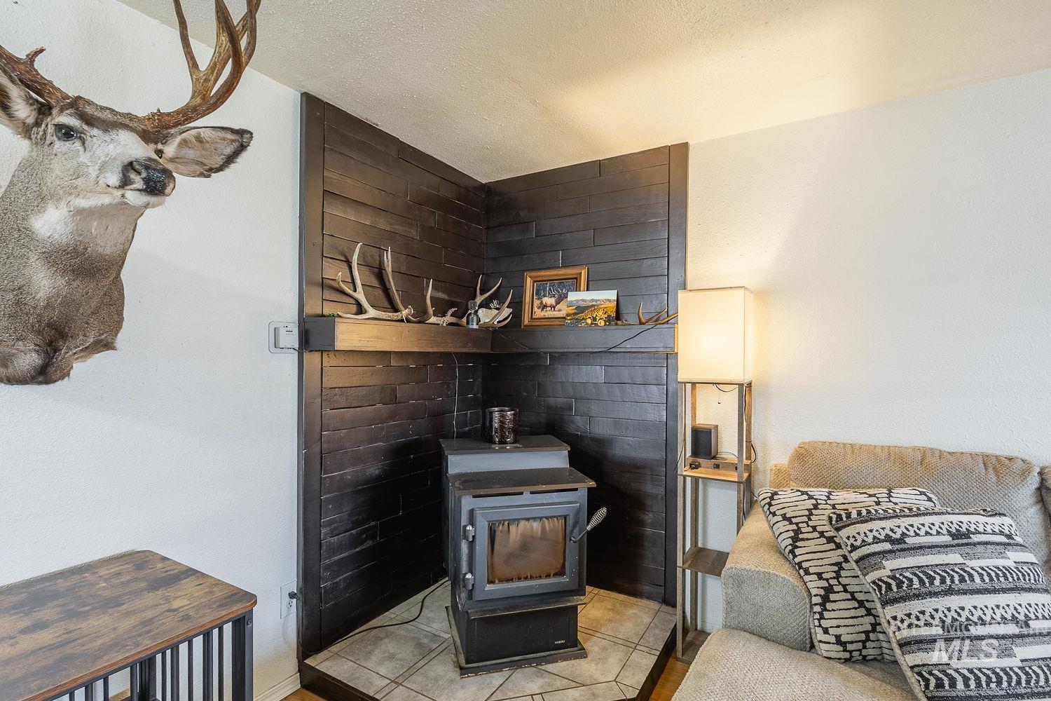 Living area with light tile patterned floors, a textured ceiling, and a wood stove