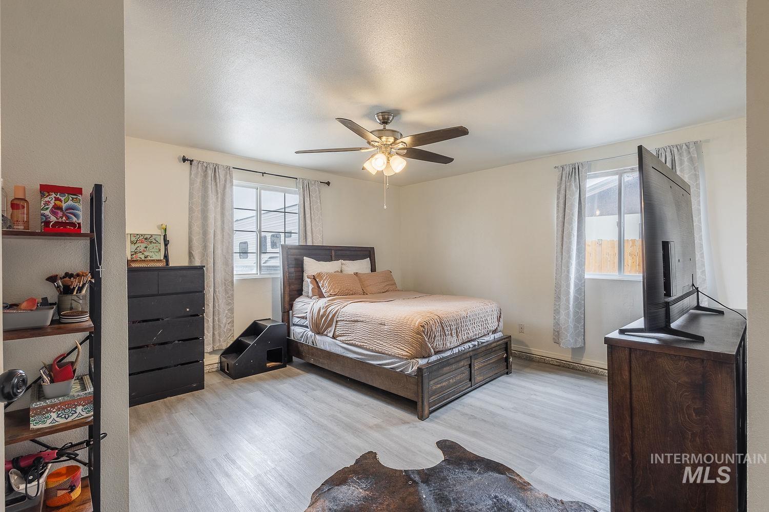 Bedroom featuring light wood-style floors, a ceiling fan, and a textured ceiling