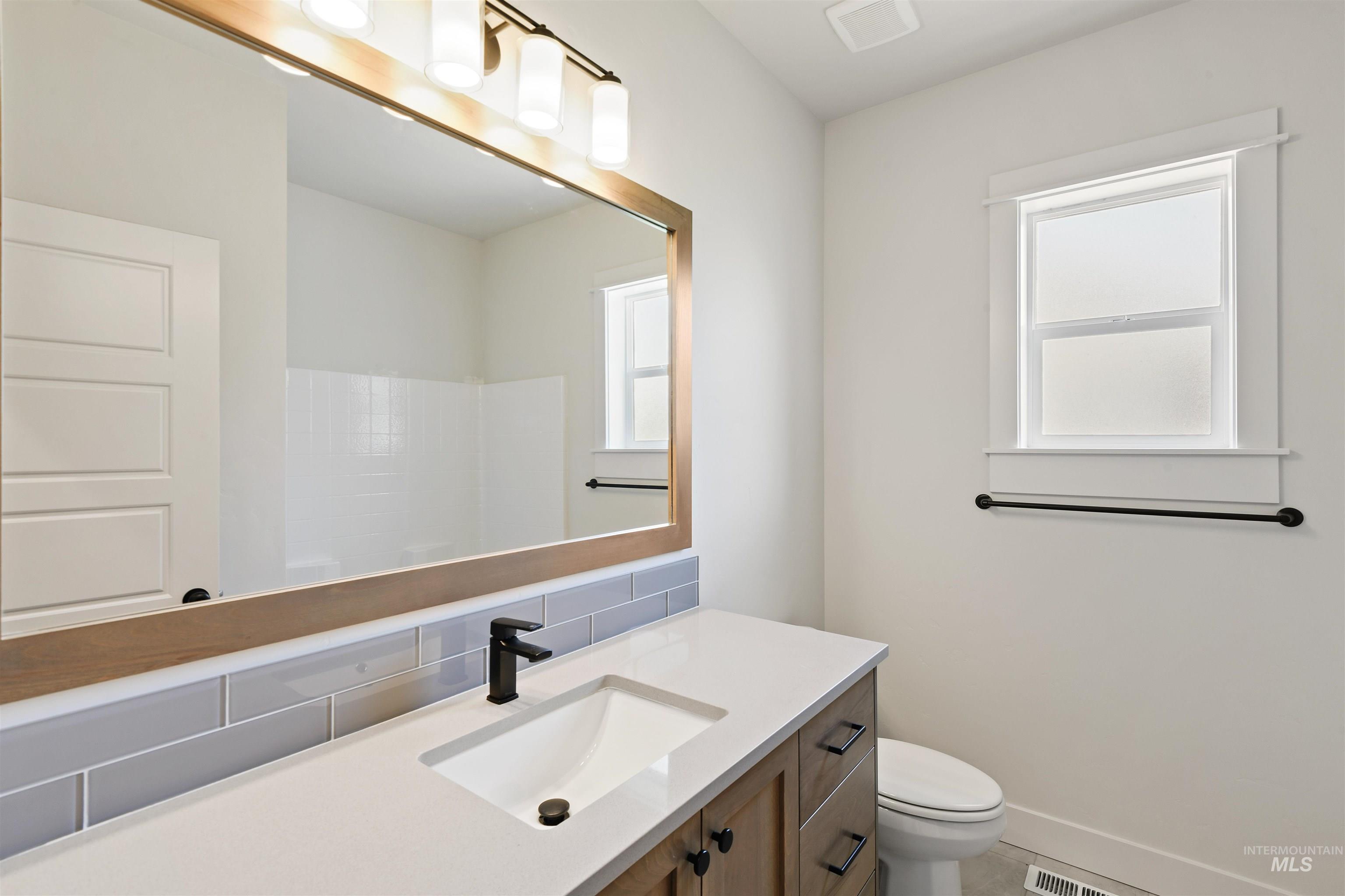 Full bath featuring vanity, healthy amount of natural light, decorative backsplash, and a shower