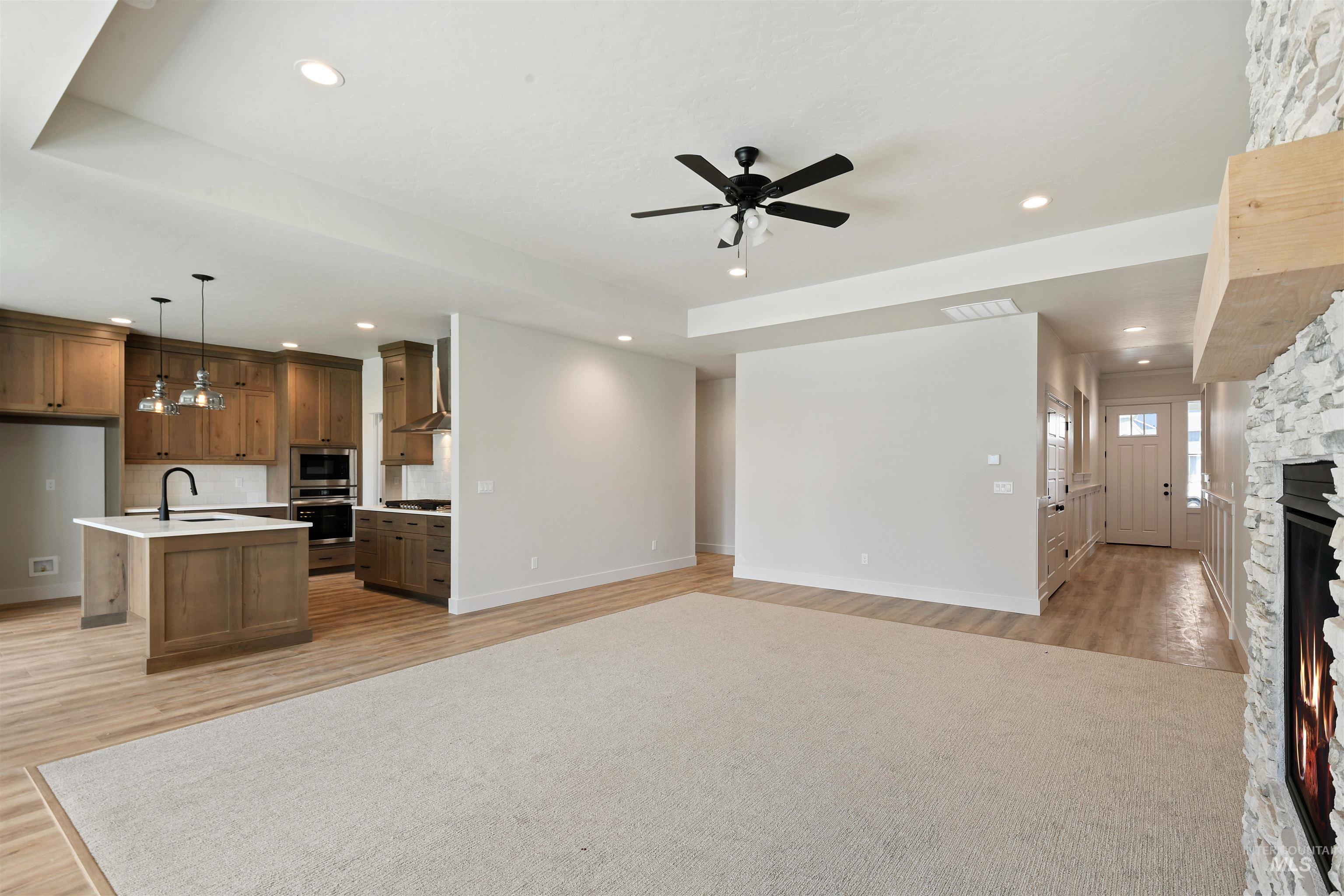 Kitchen featuring open floor plan, stainless steel appliances, light wood-style flooring, light countertops, and ceiling fan