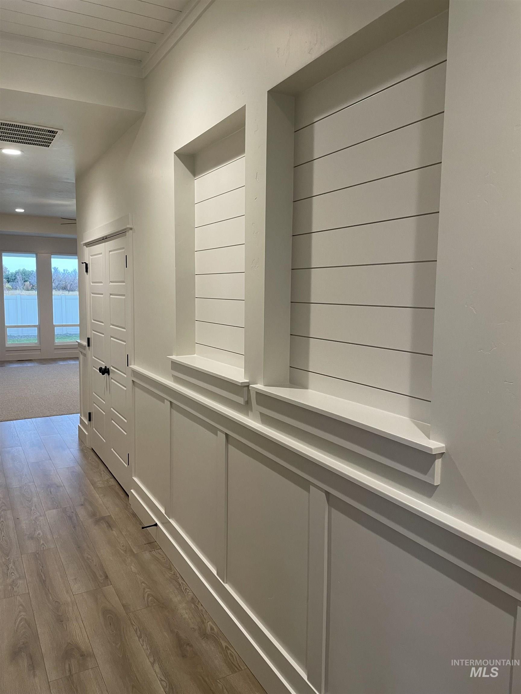 Hall featuring dark wood finished floors, crown molding, and wainscoting