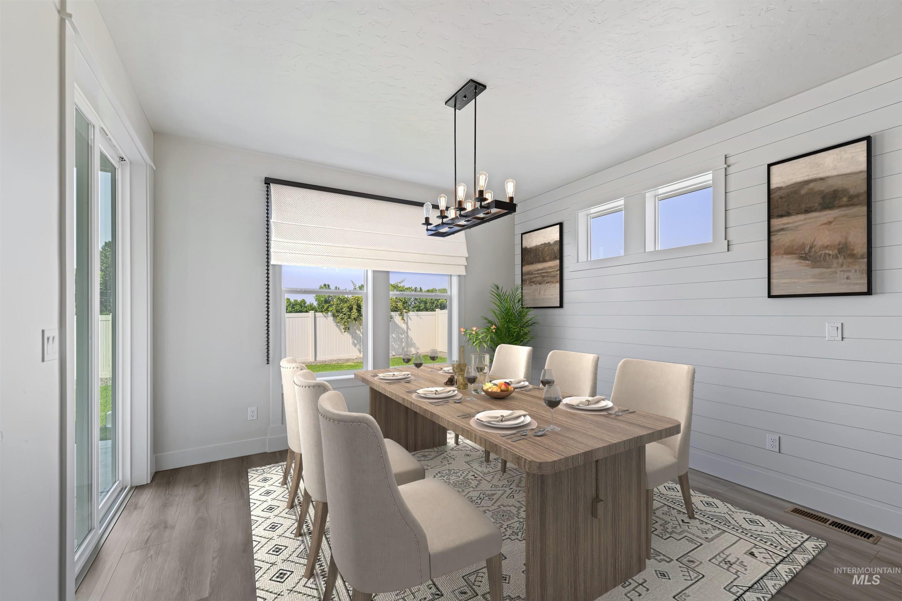 Dining room featuring light wood-style flooring, a chandelier, and wooden walls