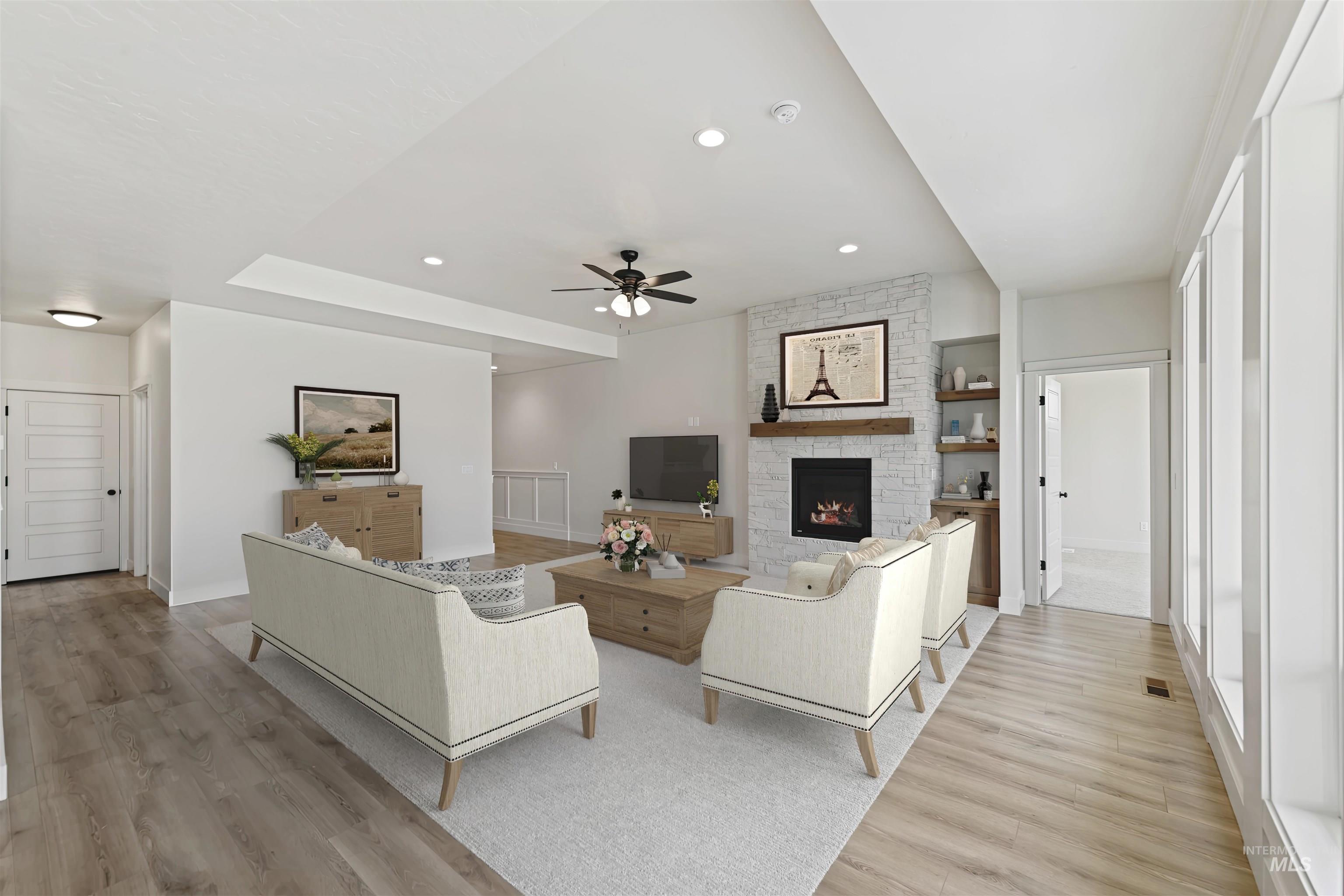 Living area featuring a ceiling fan, light wood finished floors, a stone fireplace, and recessed lighting