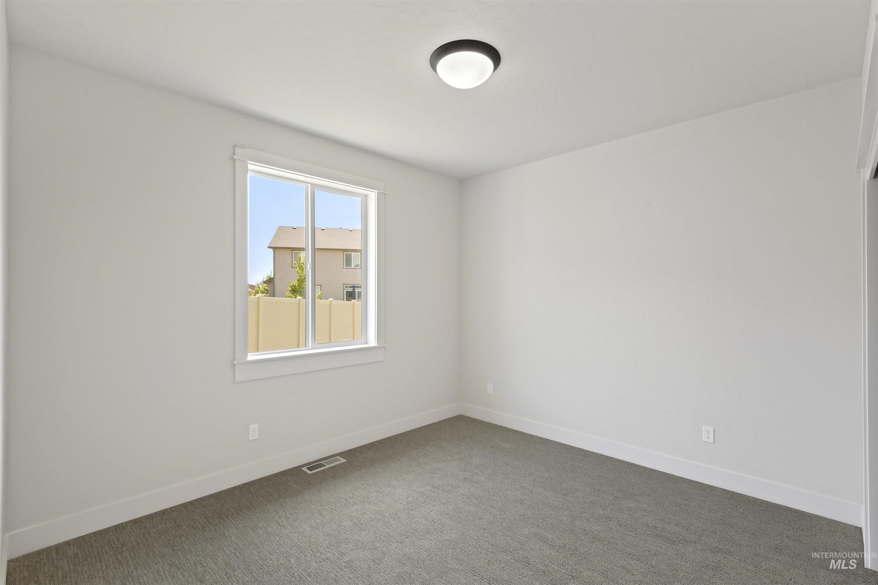 Unfurnished room featuring dark colored carpet and baseboards