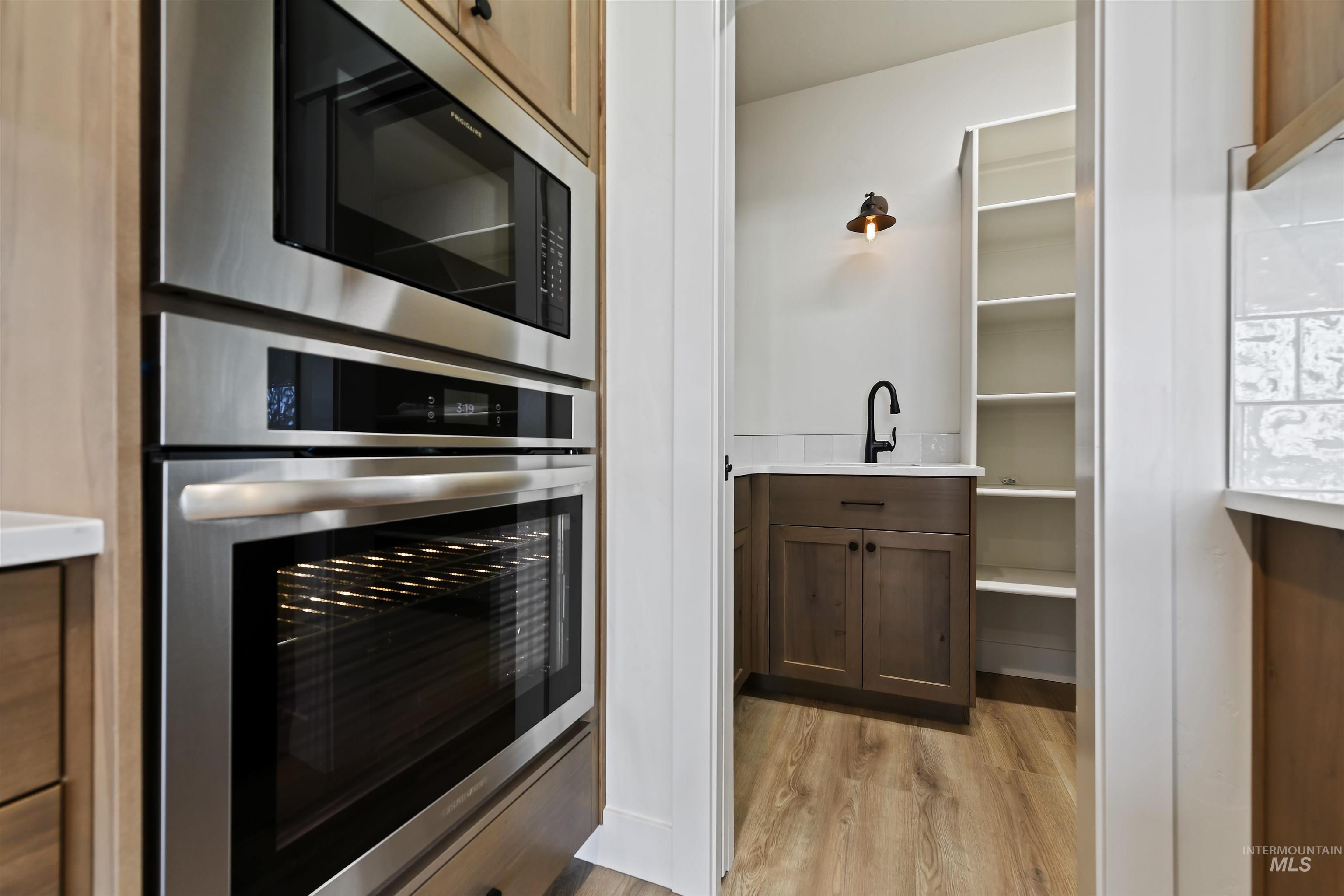 Kitchen with appliances with stainless steel finishes, light wood-type flooring, light countertops, and open shelves