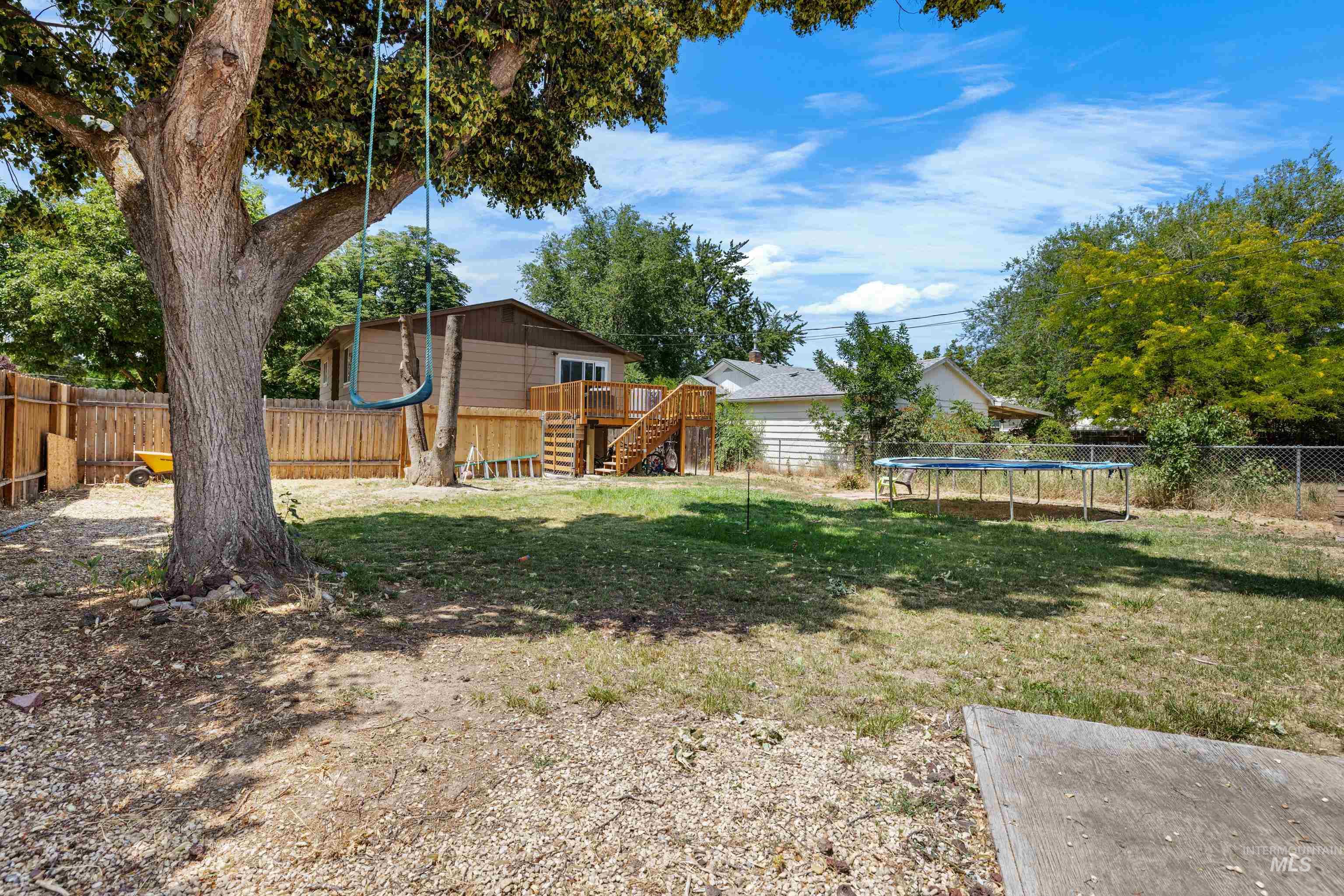 Fenced backyard with a trampoline, stairway, and a deck