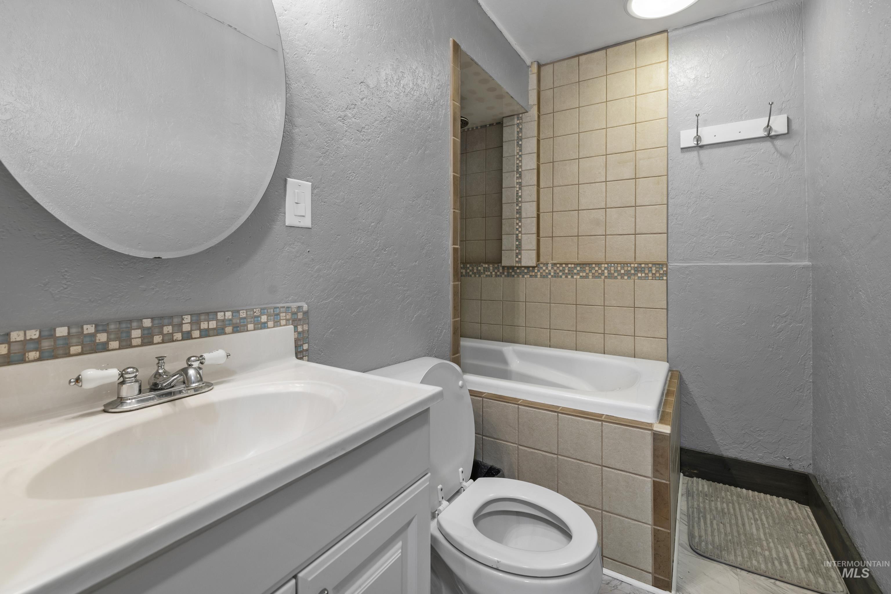 Bathroom featuring a textured wall and vanity
