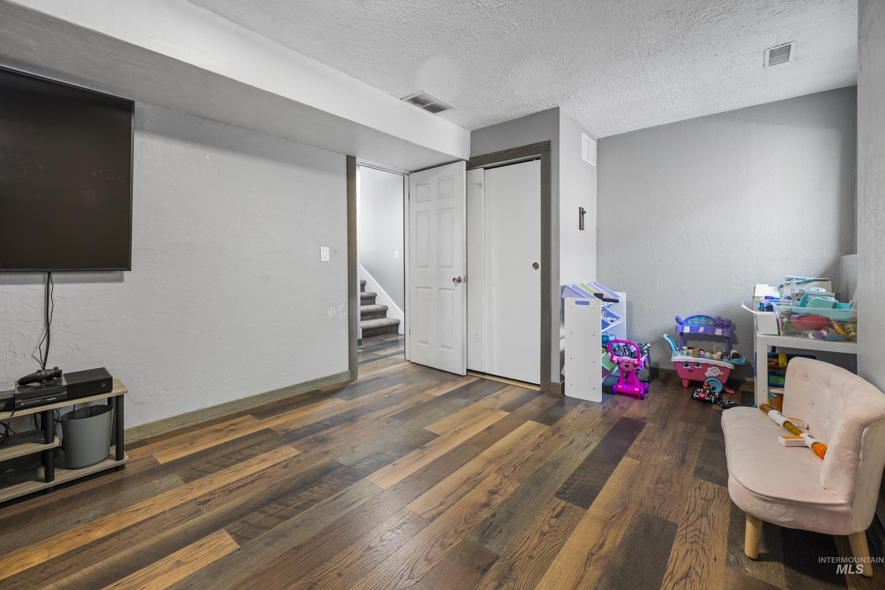 Playroom with wood finished floors and a textured ceiling