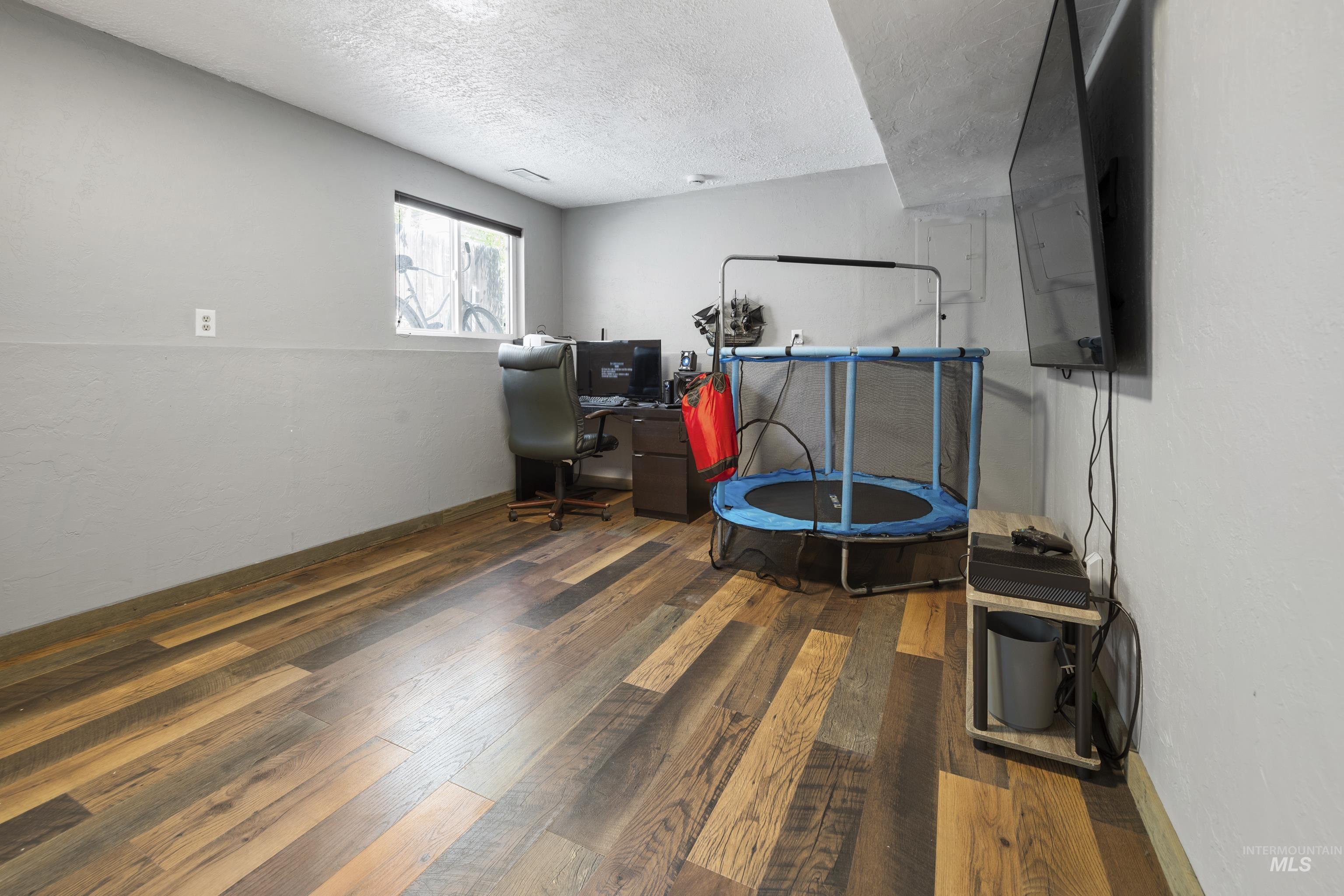 Basement with a textured ceiling, hardwood / wood-style floors, and an office area