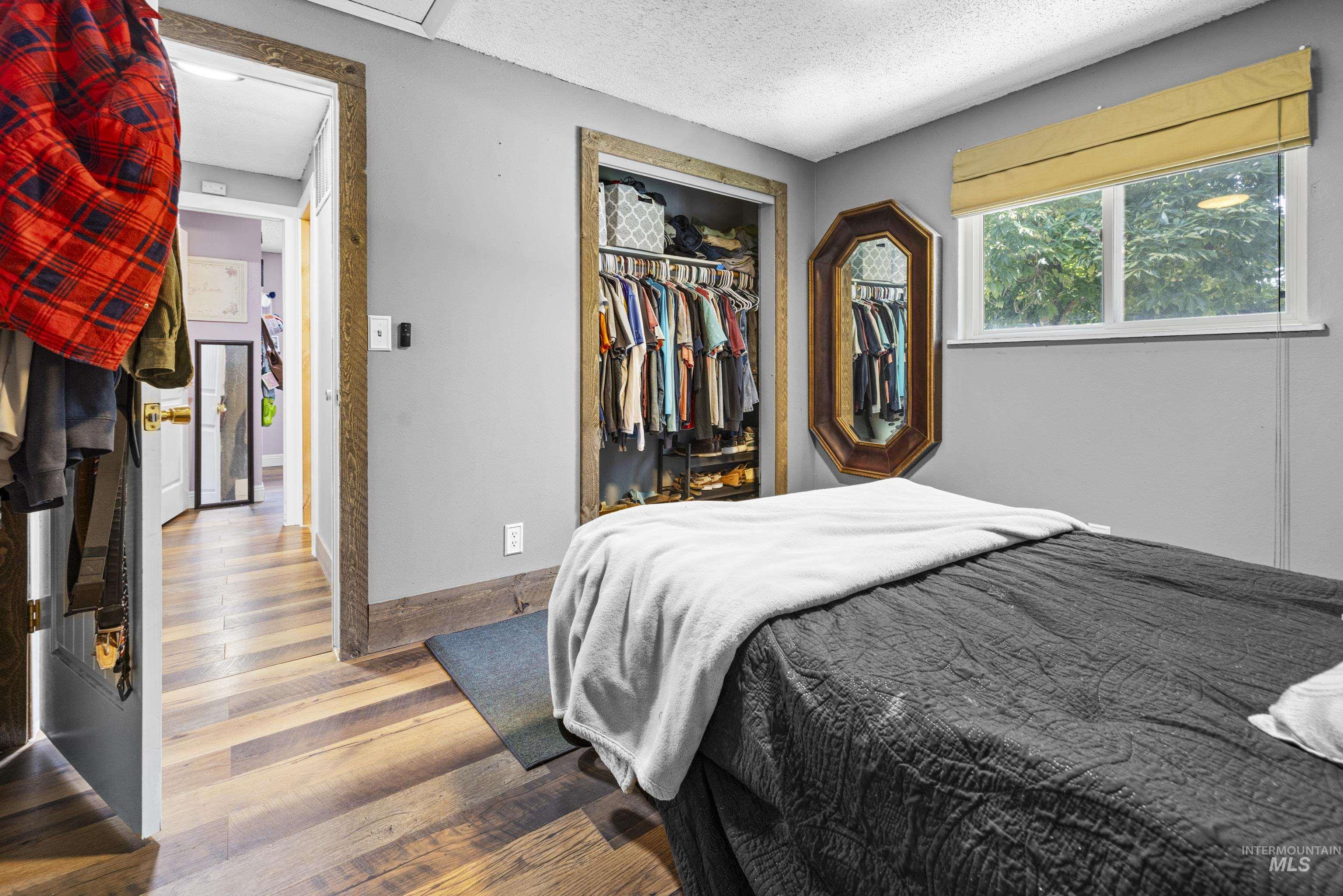 Bedroom with wood finished floors, a textured ceiling, and a closet