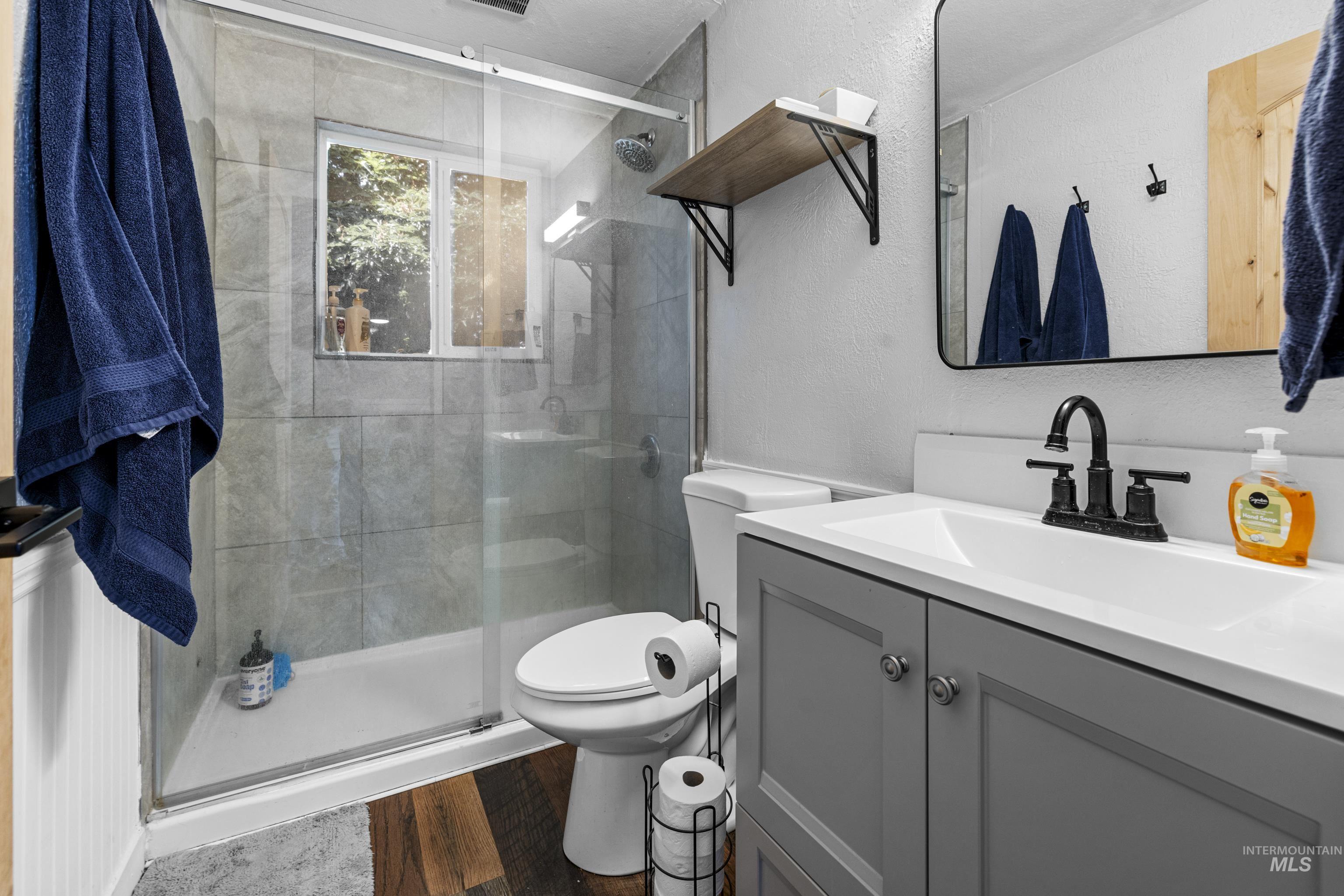 Full bath featuring wood finished floors, vanity, and a stall shower
