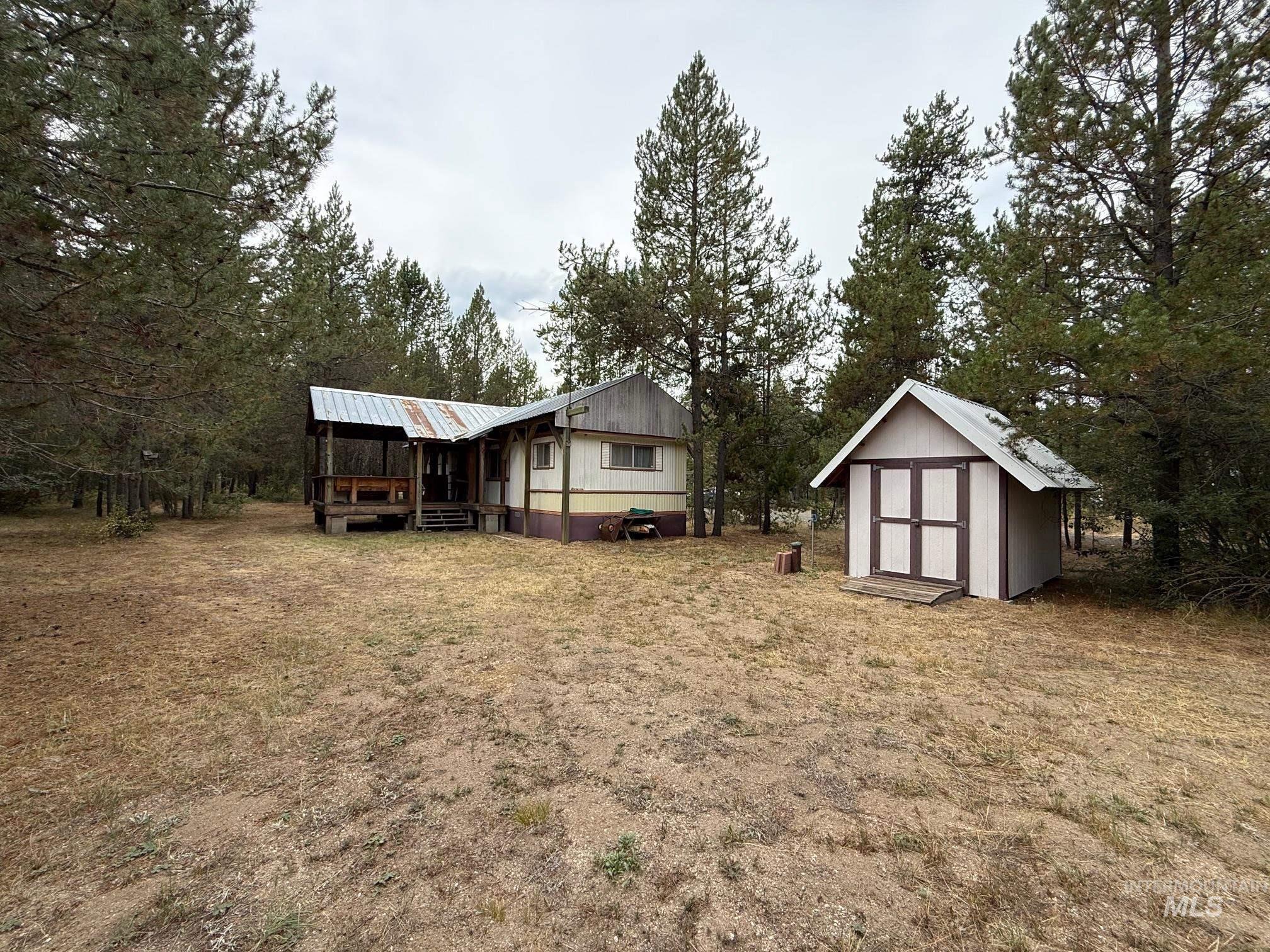 View of green lawn with a shed and view of wooded area