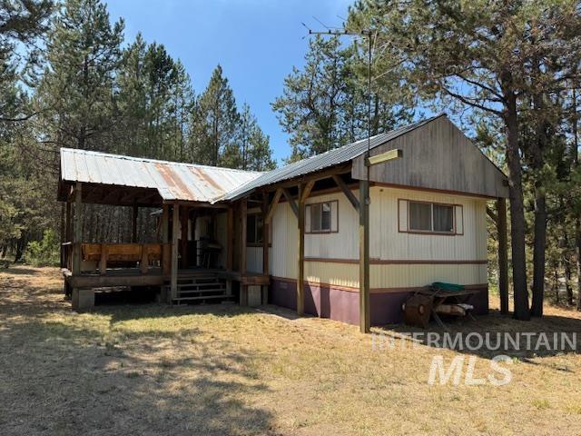 View of front of property with a wooden deck, a metal roof, and a front yard
