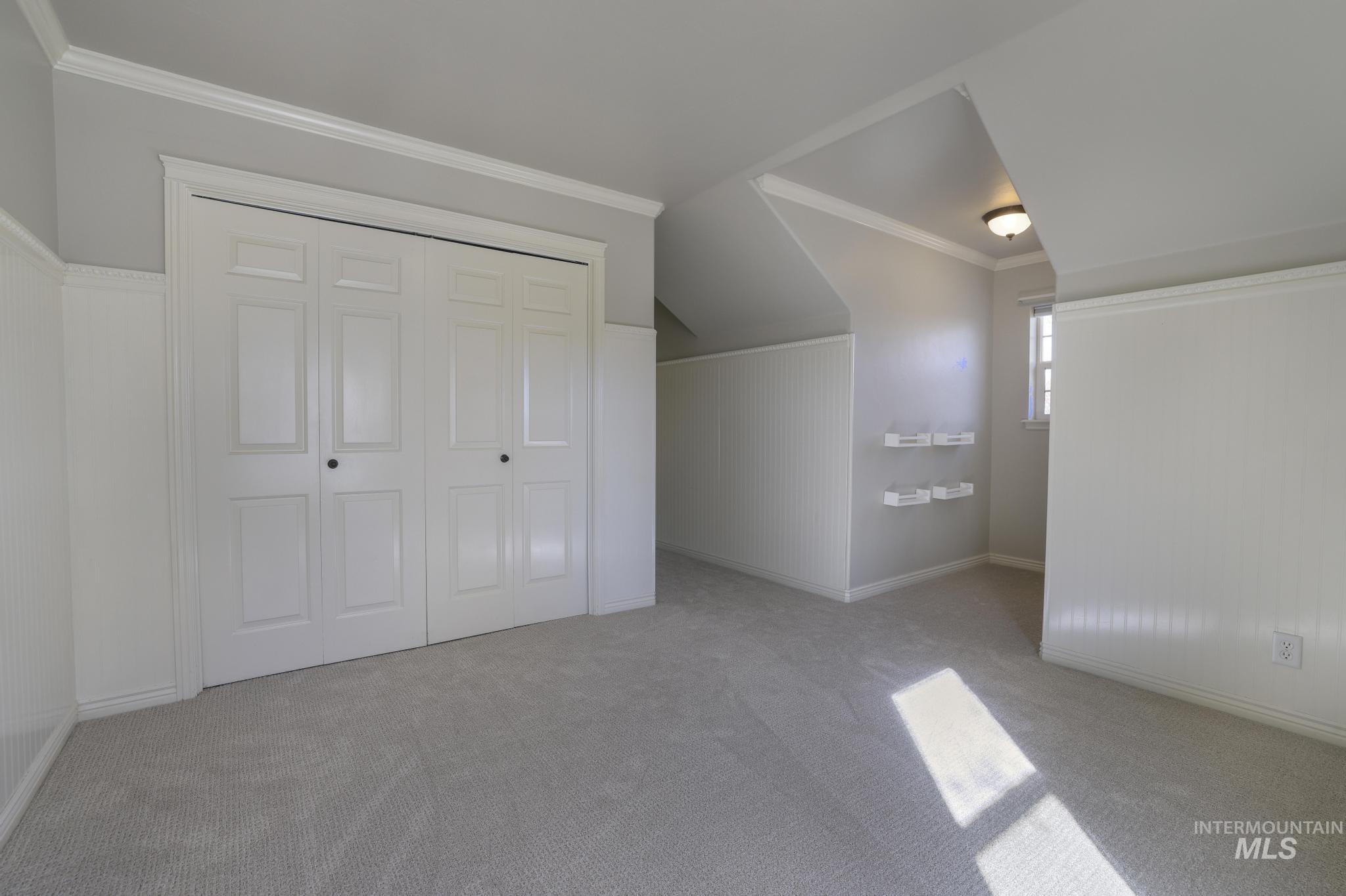 Bonus room featuring carpet flooring, wooden walls, and wainscoting