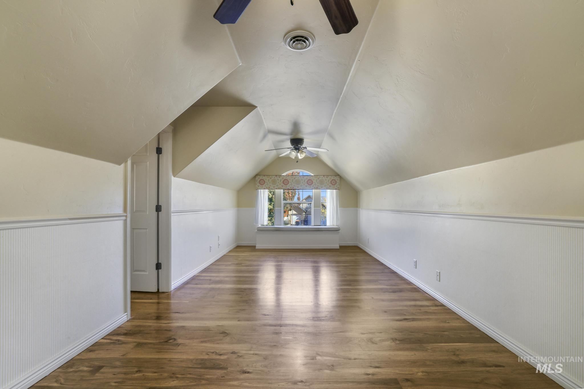 Bonus room with dark wood-type flooring, ceiling fan, and lofted ceiling