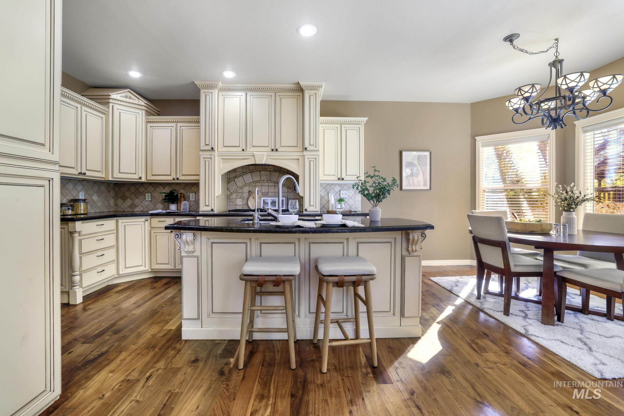 Kitchen with Walnut hardwood floors, gas cook top, integrated ventilation hood system, granite countertops, tile back splash