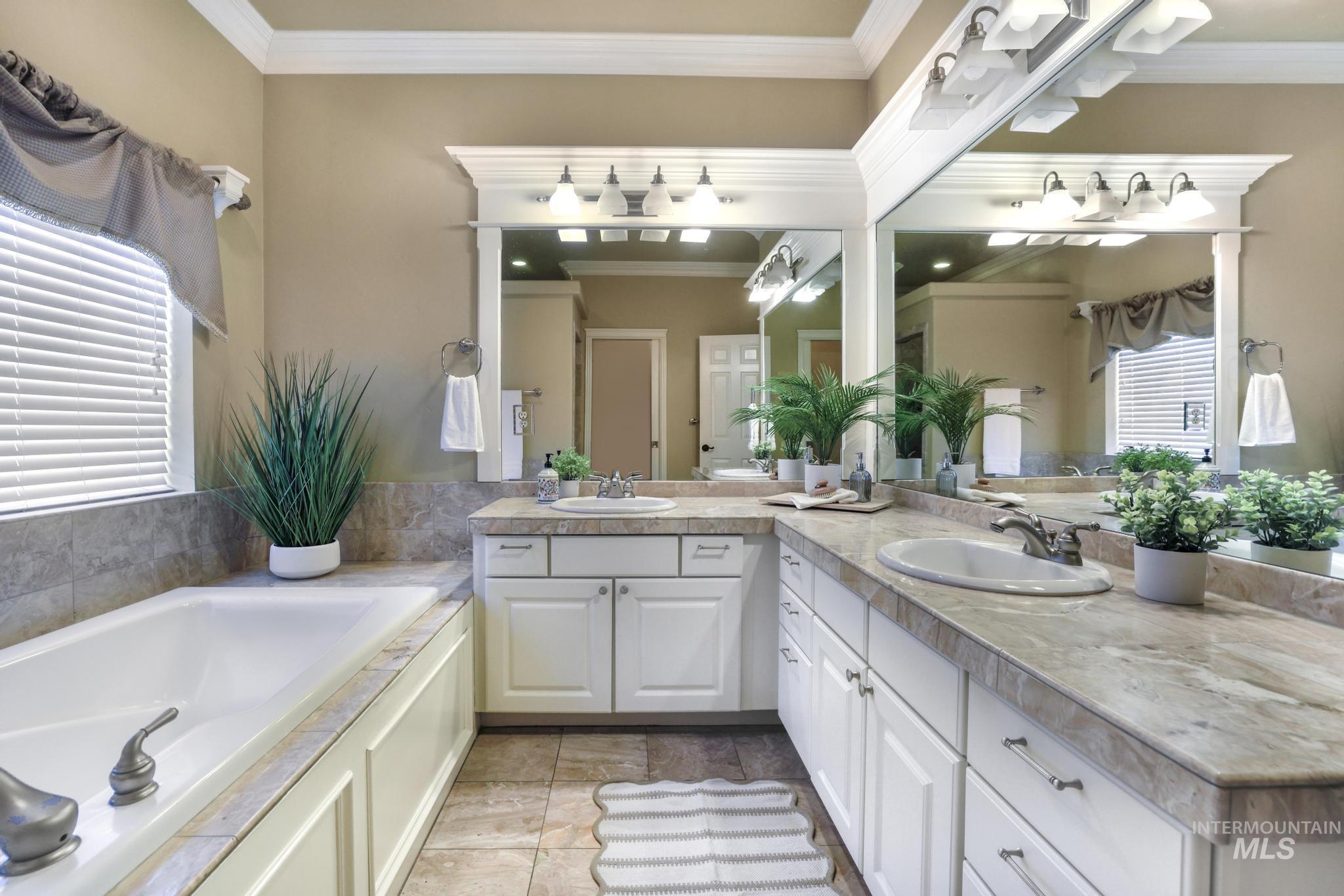 Full bath Room featuring spacious Marble countertops with double vanities, marble floors, ornamental molding, a large garden tub.