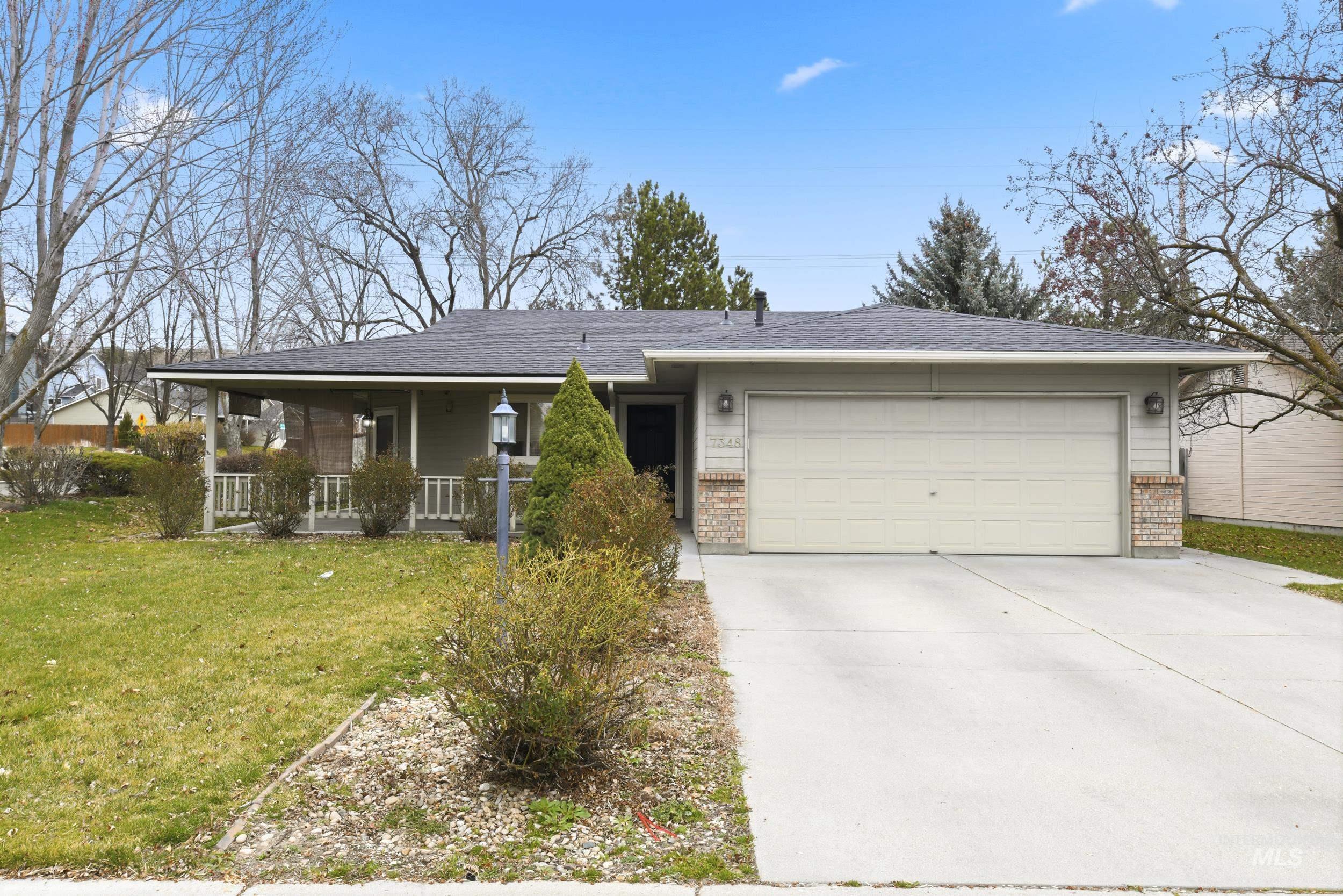Ranch-style house featuring a front yard, an attached garage, concrete driveway, a porch, and brick siding