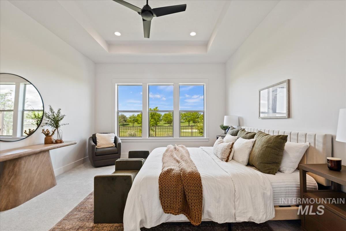 Spacious room featuring a tray ceiling with recessed lighting and a ceiling fan
