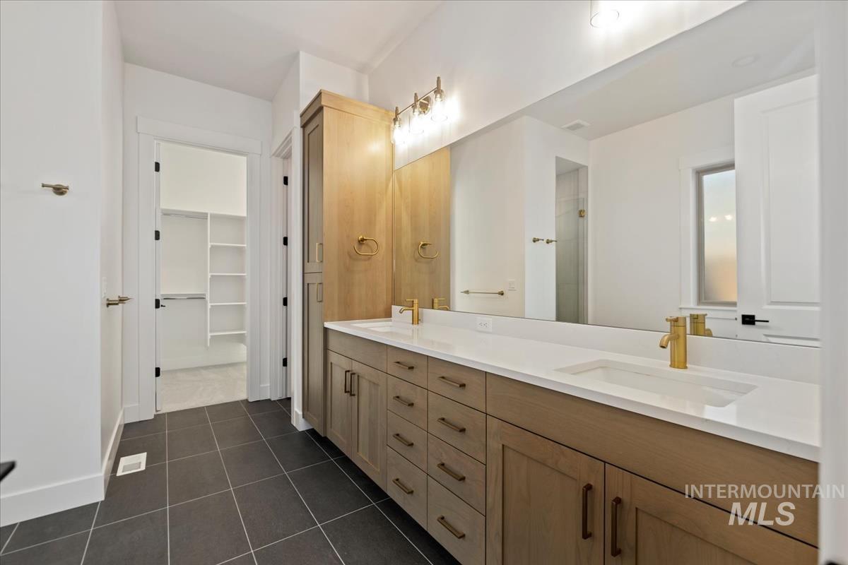 Dual vanity with white countertops, undermount sinks, and gold-tone fixtures