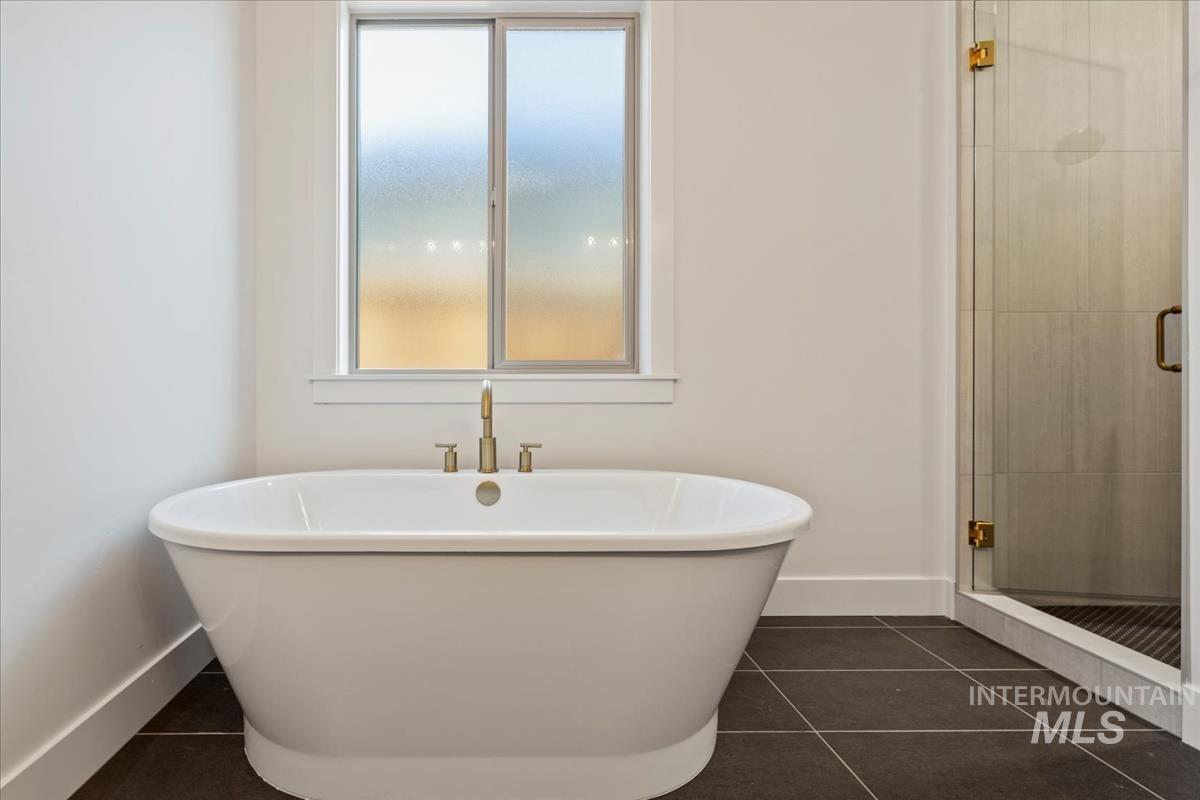 Freestanding soaking tub with brass fixtures, under a frosted sliding window