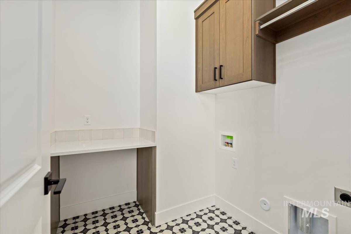 Utility space featuring patterned floor tile, a built-in counter with a white surface, and an upper wood-finish storage cabinet