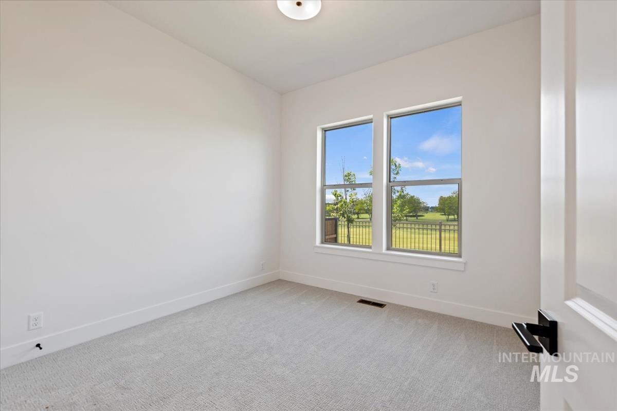 Bright room with two large windows, light grey carpeting, white baseboards, and a contemporary ceiling light fixture