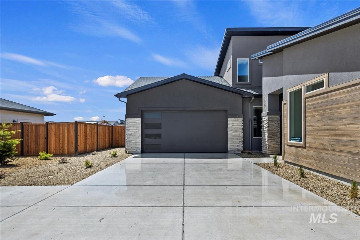 Contemporary exterior featuring dark gray stucco siding and a prominent two-car garage with frosted glass panels