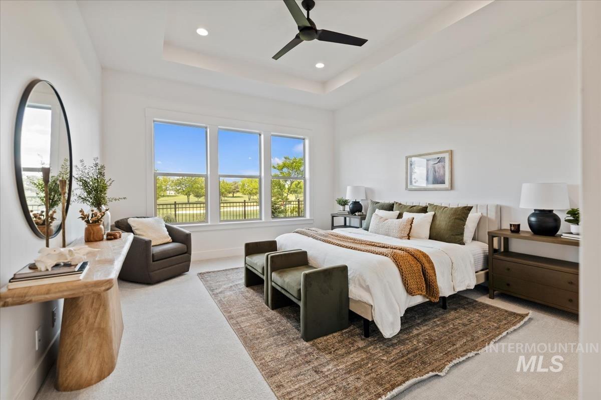 Spacious room featuring multiple large windows, a tray ceiling with recessed lighting, a ceiling fan, and carpeted flooring