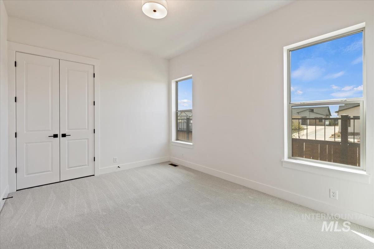 Neutral-toned carpeting paired with white walls, baseboards, and window trim