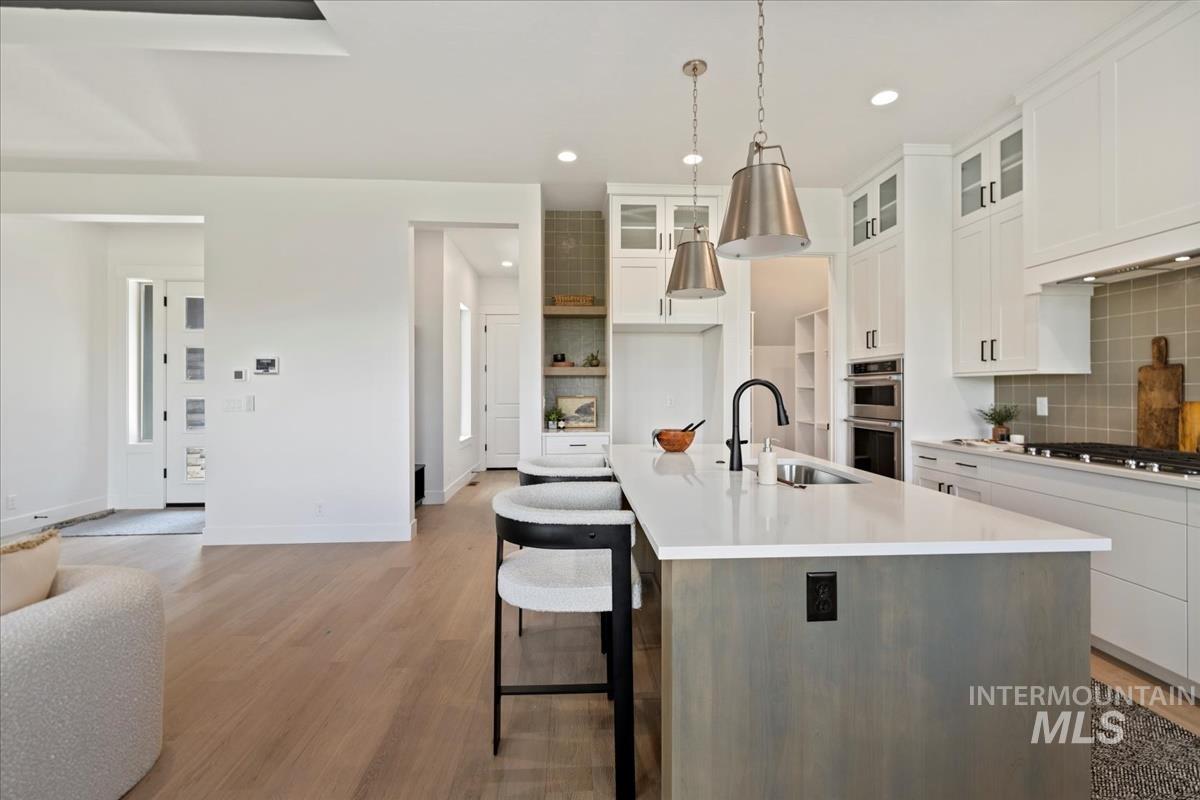 Contemporary kitchen featuring a large island with a light countertop, integrated sink, and matte black faucet