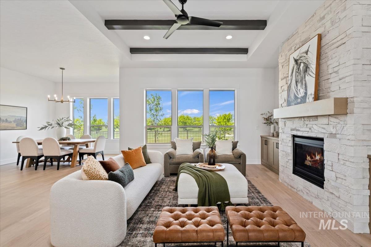 Open-concept living space featuring light wood-finish flooring and a white stacked stone fireplace with an integrated firebox