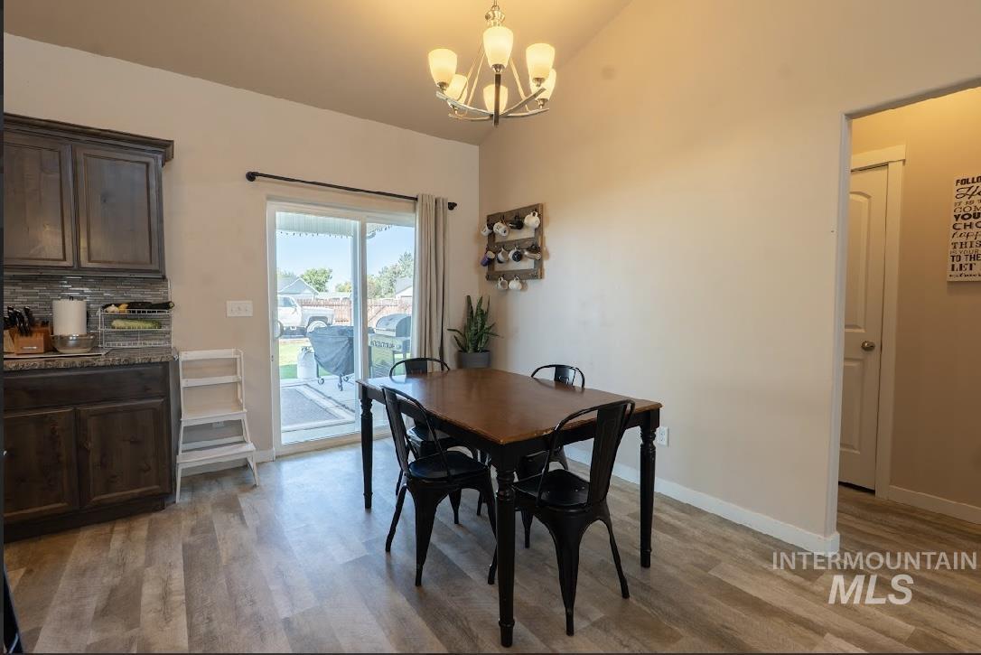 Dining area with light wood finished floors, a chandelier, and lofted ceiling