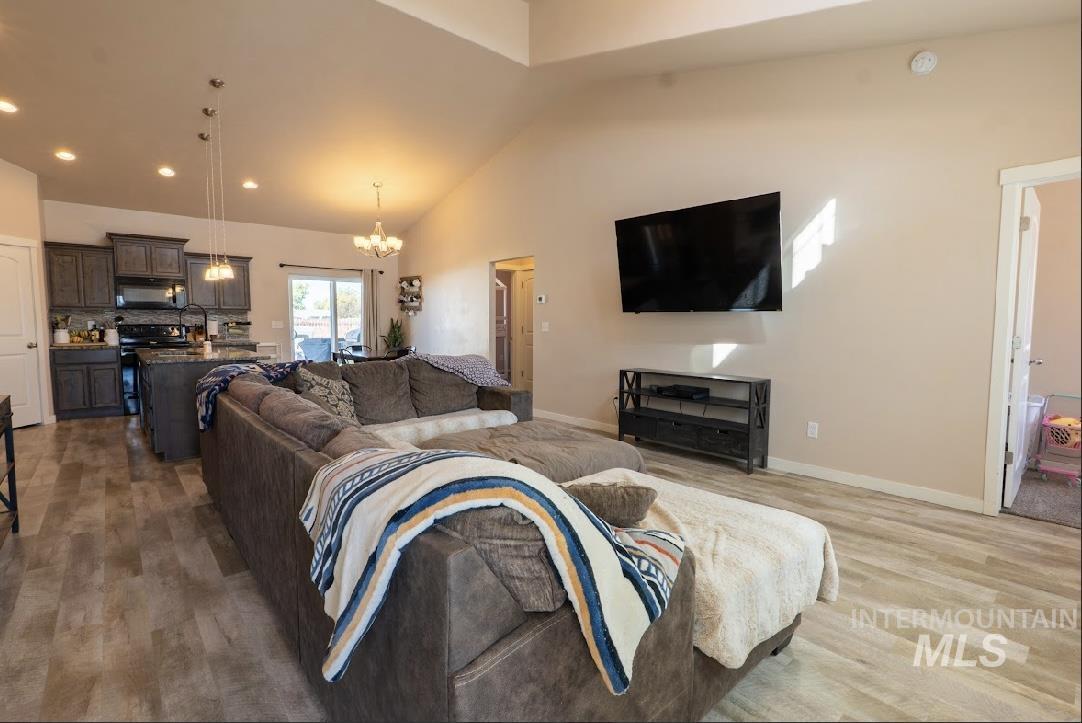 Living room with recessed lighting, a chandelier, high vaulted ceiling, and dark wood-style flooring
