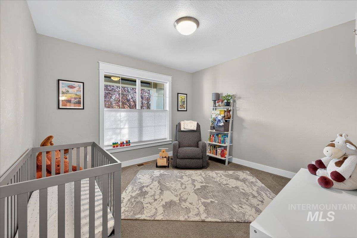 Bedroom featuring carpet flooring, a nursery area, and a textured ceiling