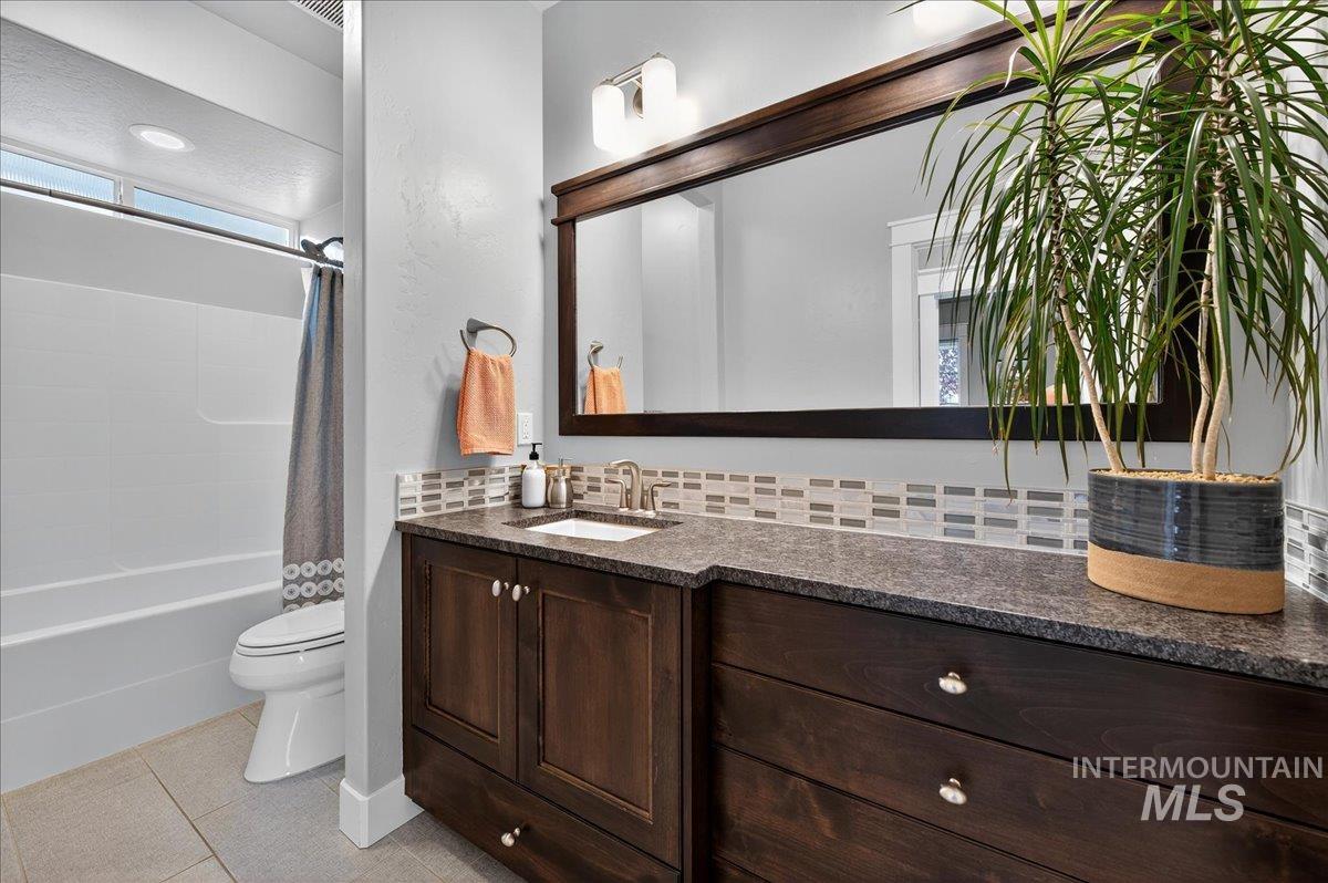 Full bathroom featuring light tile patterned flooring, shower / bath combination with curtain, and vanity
